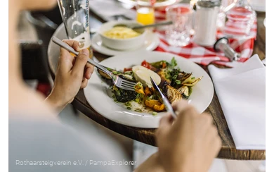 Nahaufnahme von einem Teller mit Antipasti und Händen die Besteck halten