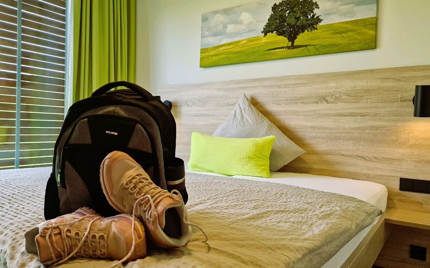 Zimmer im Hotel Fünf10 mit Wanderschuhen und Rucksack auf dem Bett