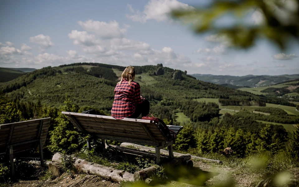 Wanderin sitz auf einer Bank und schaut in der Ferne auf die Bruchhauser Steine