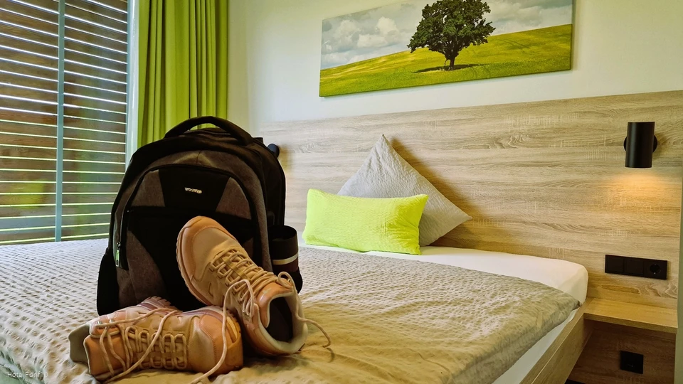 Zimmer im Hotel Fünf10 mit Wanderschuhen und Rucksack auf dem Bett